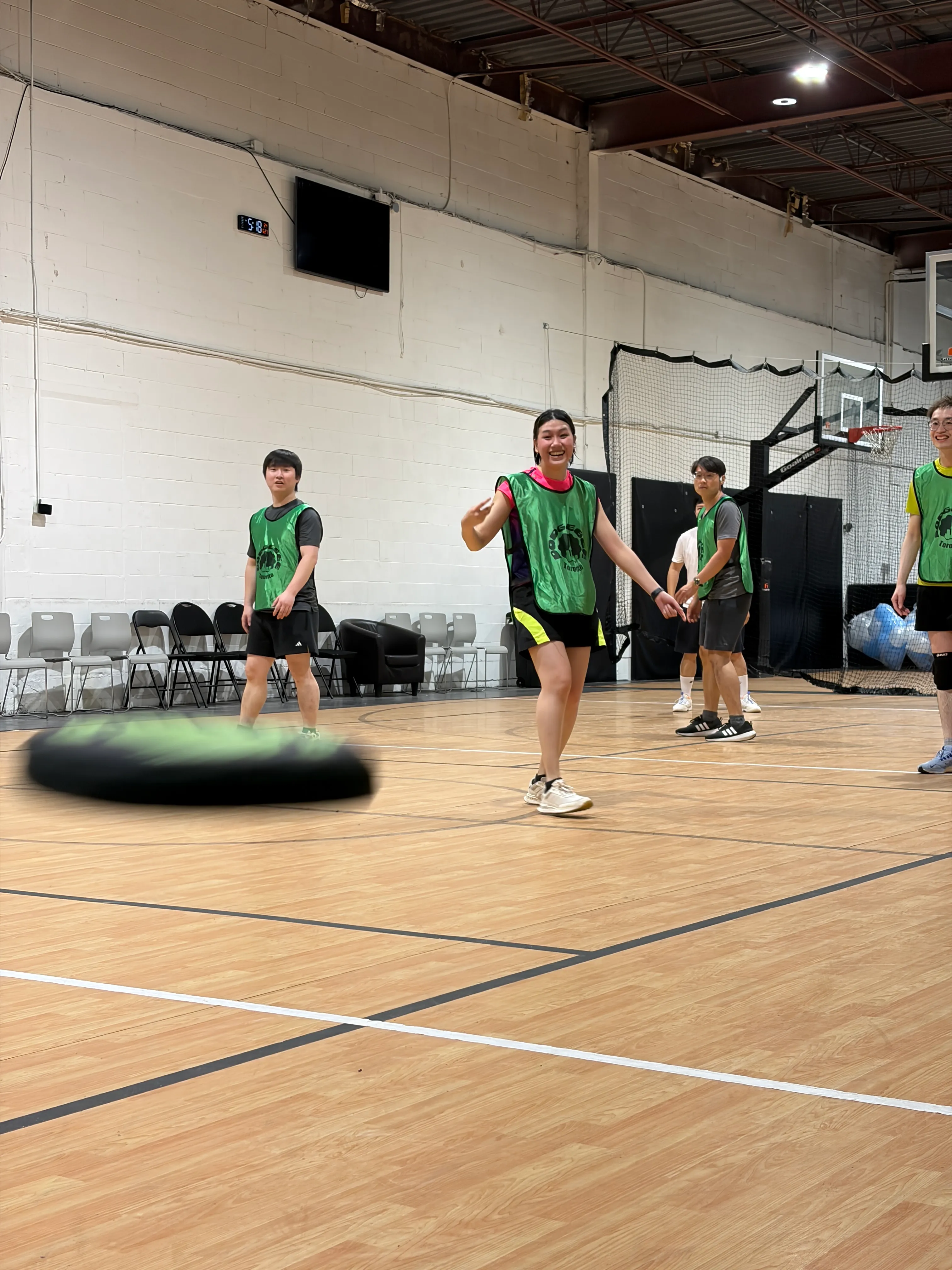 A soft Dodgebee disc flies across the court toward smiling players.